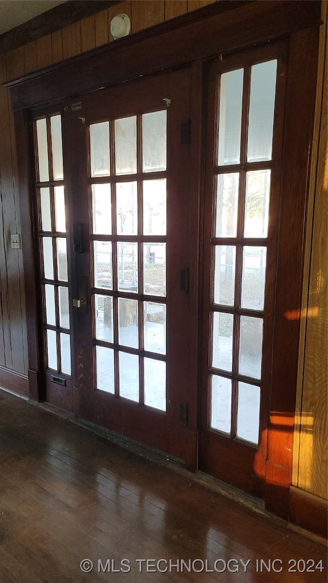 doorway with wood walls, dark wood-type flooring, and french doors