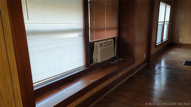 room details featuring wooden walls, cooling unit, and wood-type flooring