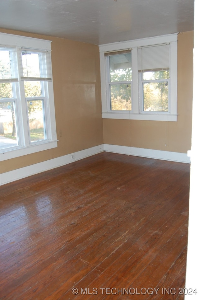 empty room featuring a wealth of natural light and dark hardwood / wood-style floors