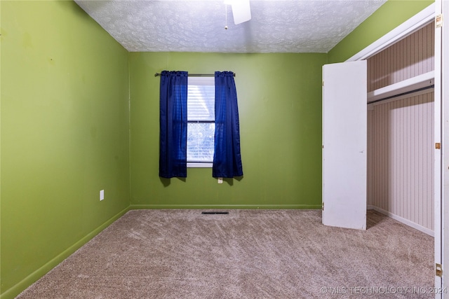 unfurnished bedroom featuring a textured ceiling, a closet, ceiling fan, and light colored carpet