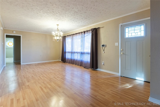 foyer entrance with crown molding, wood-type flooring, a textured ceiling, and an inviting chandelier