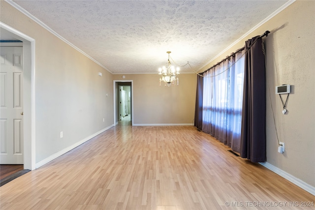 empty room with wood-type flooring, a textured ceiling, an inviting chandelier, and ornamental molding