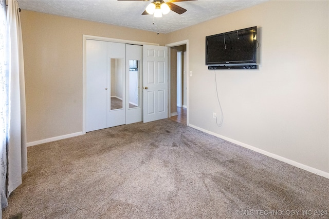 unfurnished bedroom featuring carpet flooring, a textured ceiling, a closet, and ceiling fan