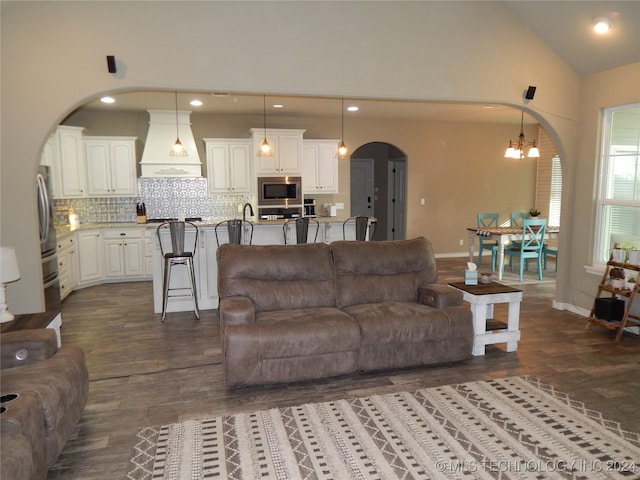 living room with lofted ceiling, dark wood-type flooring, and a chandelier