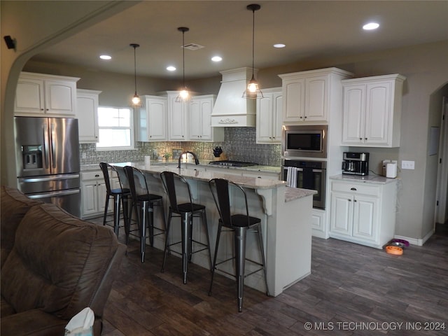 kitchen featuring custom exhaust hood, appliances with stainless steel finishes, decorative light fixtures, dark hardwood / wood-style flooring, and white cabinetry