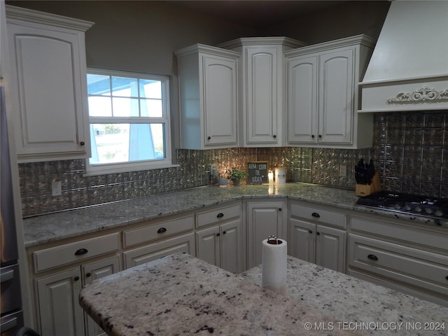 kitchen with premium range hood, white cabinetry, and tasteful backsplash