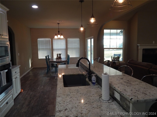 kitchen featuring sink, stainless steel appliances, dark hardwood / wood-style floors, an island with sink, and pendant lighting