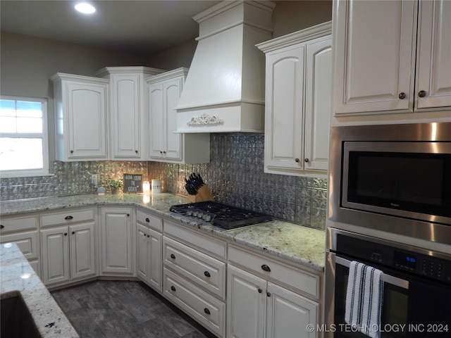 kitchen featuring premium range hood, white cabinets, and appliances with stainless steel finishes