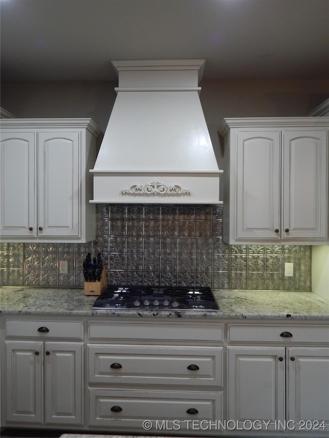 kitchen featuring white cabinets, decorative backsplash, premium range hood, and black gas cooktop