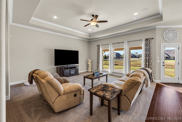 living room with hardwood / wood-style flooring, ceiling fan, ornamental molding, and a tray ceiling