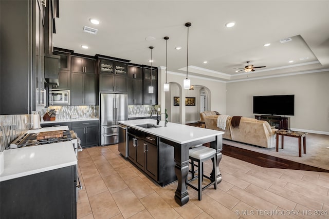 kitchen with ceiling fan, sink, pendant lighting, a kitchen island with sink, and appliances with stainless steel finishes