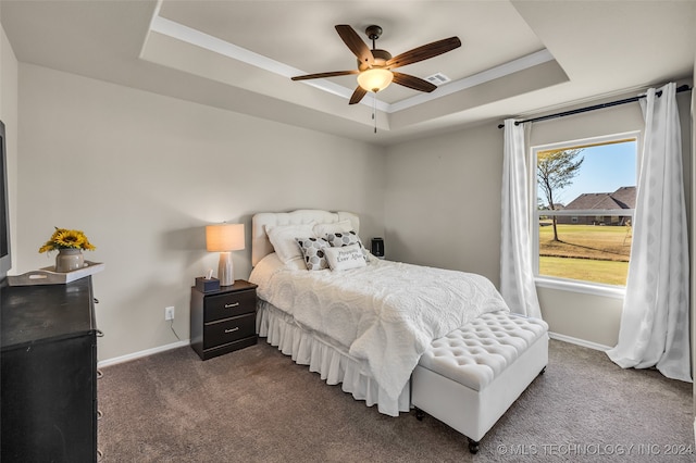 carpeted bedroom featuring a tray ceiling and ceiling fan