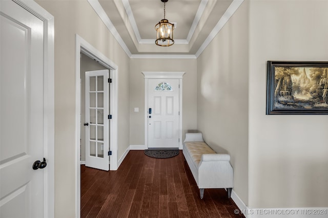 entrance foyer featuring an inviting chandelier, ornamental molding, dark wood-type flooring, and a tray ceiling