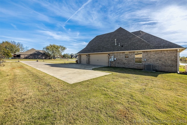 back of property with a yard, cooling unit, and a garage