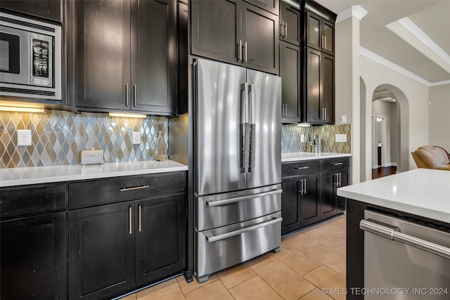 kitchen featuring tasteful backsplash, light tile patterned floors, stainless steel appliances, and ornamental molding