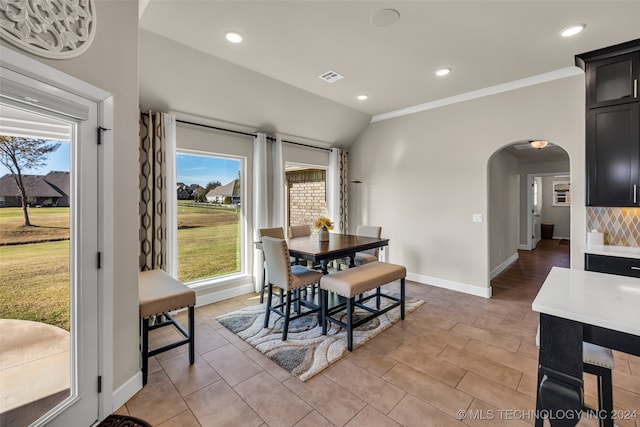 dining room with crown molding, a wealth of natural light, and vaulted ceiling