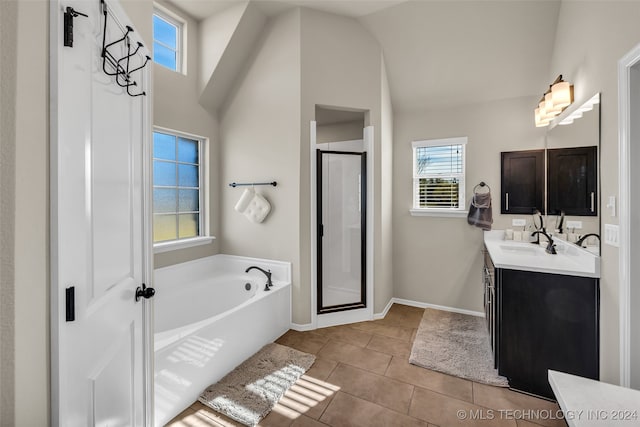 bathroom with tile patterned flooring, vanity, lofted ceiling, and a wealth of natural light