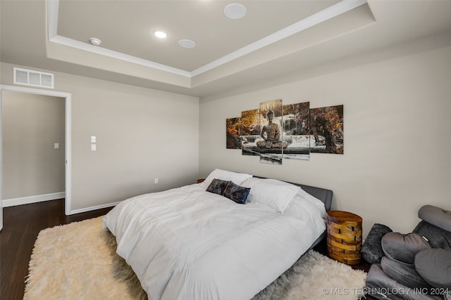 bedroom featuring dark hardwood / wood-style flooring and a tray ceiling