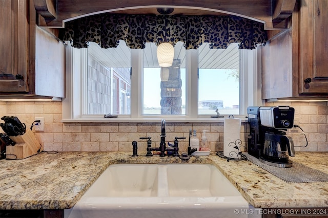 kitchen featuring tasteful backsplash, light stone counters, and sink