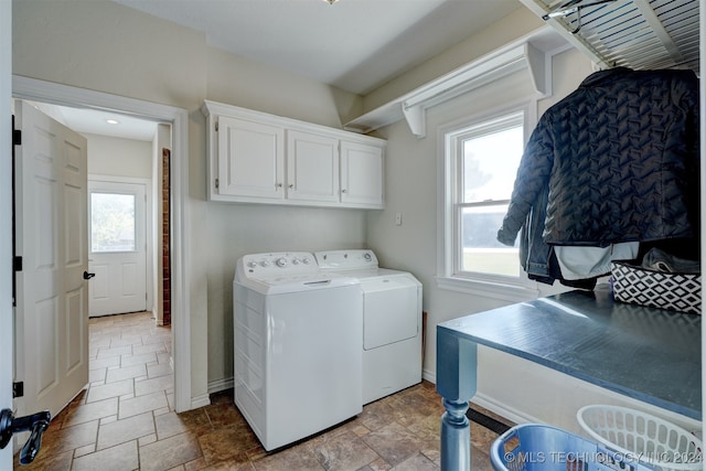 laundry area featuring washing machine and dryer, cabinets, and a healthy amount of sunlight