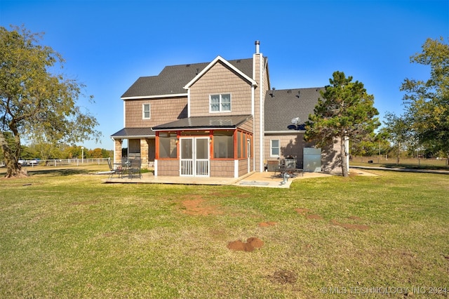 rear view of house with a sunroom, a yard, and a patio