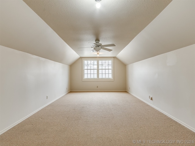 bonus room with ceiling fan, light colored carpet, a textured ceiling, and vaulted ceiling