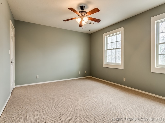 carpeted spare room with a wealth of natural light and ceiling fan