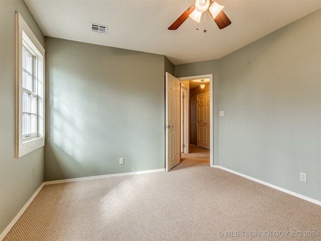 spare room with ceiling fan and light colored carpet