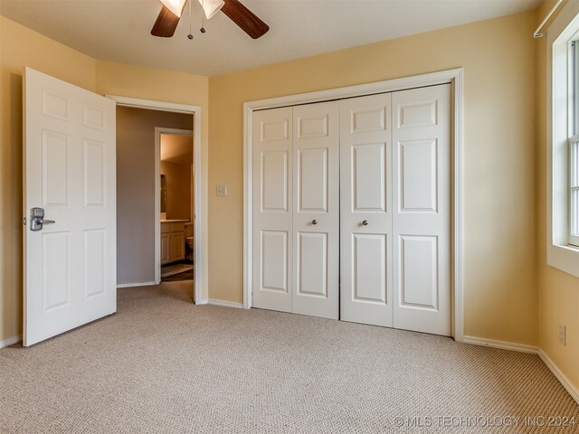 unfurnished bedroom with multiple windows, light carpet, and ceiling fan