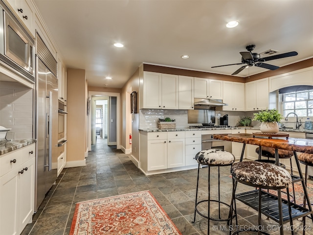 kitchen with sink, tasteful backsplash, white cabinetry, and light stone counters