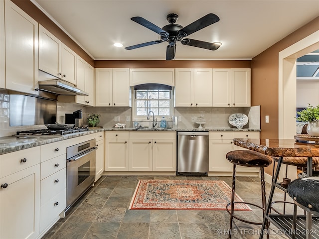 kitchen featuring ceiling fan, sink, light stone countertops, stainless steel appliances, and backsplash