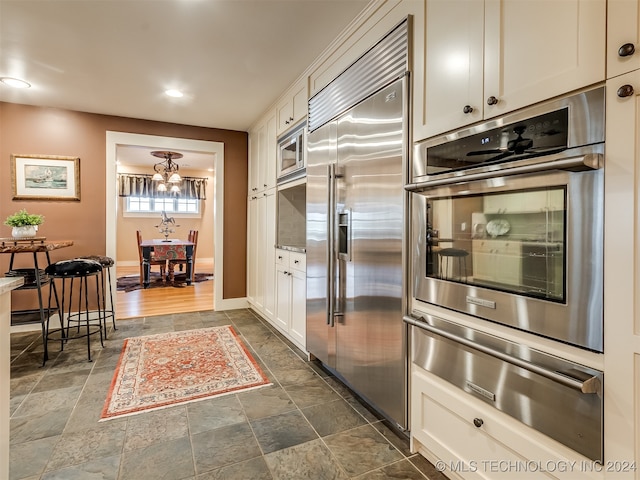 kitchen featuring built in appliances, dark hardwood / wood-style flooring, and white cabinets