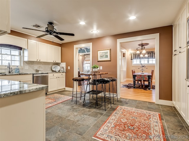 kitchen with plenty of natural light, white cabinets, stainless steel dishwasher, and sink