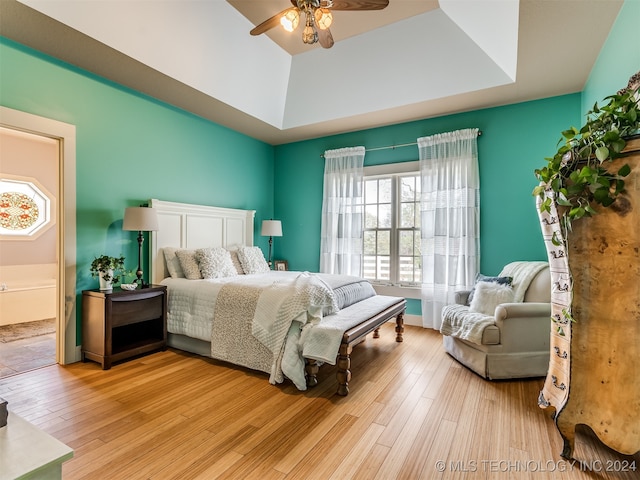 bedroom with ceiling fan, a raised ceiling, and light hardwood / wood-style flooring