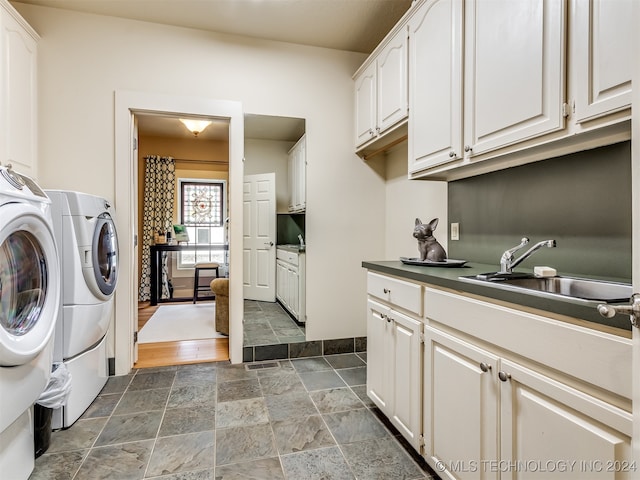 clothes washing area with washer and dryer, dark hardwood / wood-style floors, cabinets, and sink