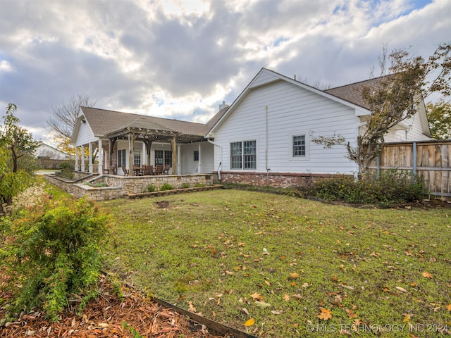 rear view of property with a pergola, a patio area, and a yard