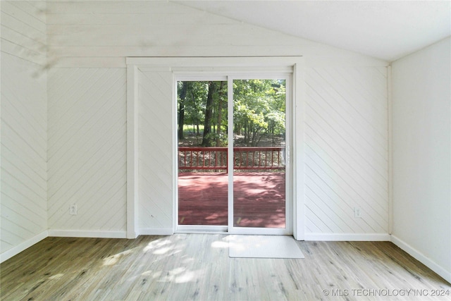 empty room featuring wooden walls, hardwood / wood-style floors, and vaulted ceiling