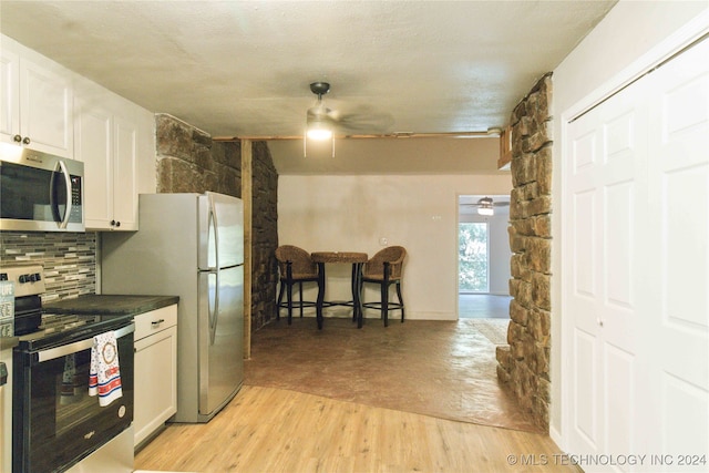 kitchen featuring white cabinets, ceiling fan, a textured ceiling, appliances with stainless steel finishes, and light hardwood / wood-style floors