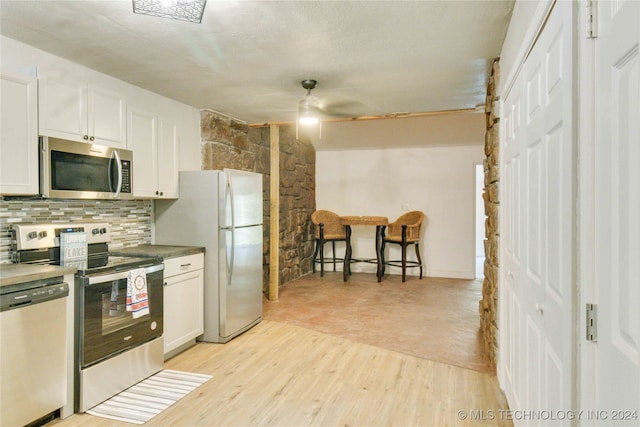 kitchen with white cabinets, appliances with stainless steel finishes, light wood-type flooring, and ceiling fan