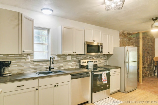 kitchen featuring tasteful backsplash, stainless steel appliances, sink, light hardwood / wood-style flooring, and white cabinets