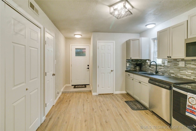 kitchen featuring a textured ceiling, sink, stainless steel appliances, and light hardwood / wood-style flooring