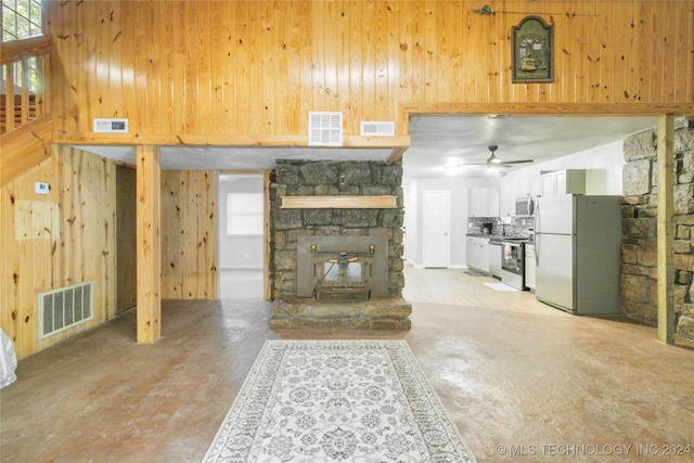 unfurnished living room featuring wood walls, a towering ceiling, and ceiling fan