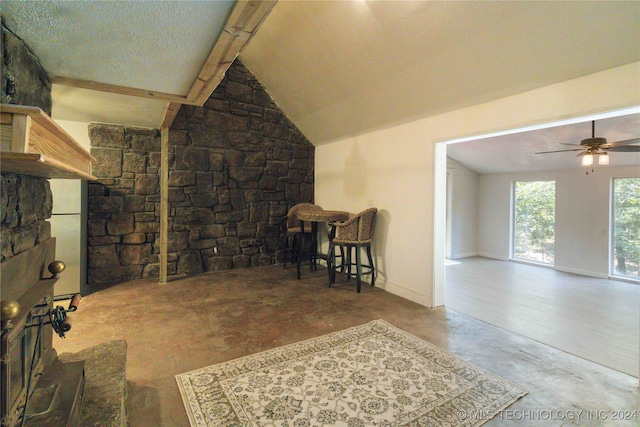 interior space featuring a textured ceiling, lofted ceiling with beams, ceiling fan, and concrete floors