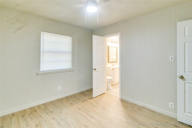 unfurnished bedroom with ceiling fan, ensuite bathroom, and light hardwood / wood-style floors