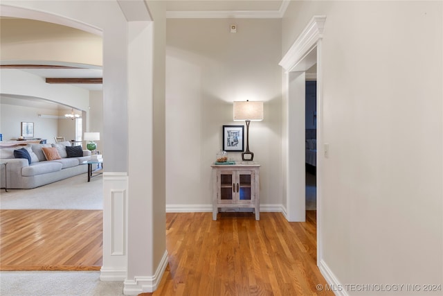 hallway with light hardwood / wood-style floors and ornamental molding