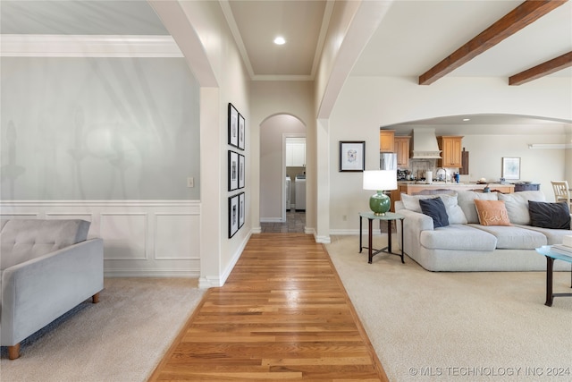 living room featuring beam ceiling, ornamental molding, and light carpet