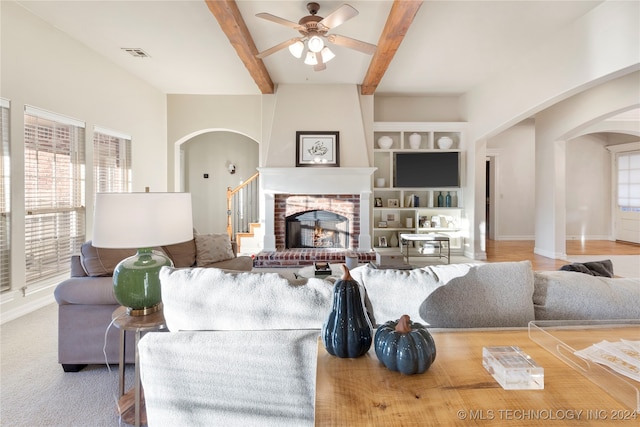 living room with beam ceiling, a brick fireplace, and ceiling fan