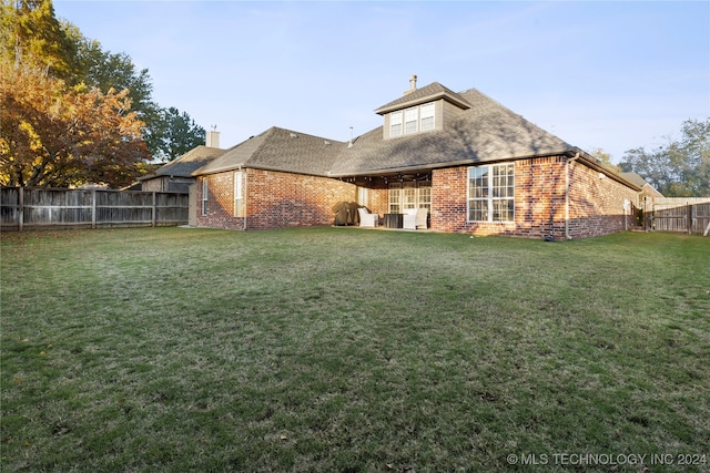 back of property featuring a lawn and ceiling fan