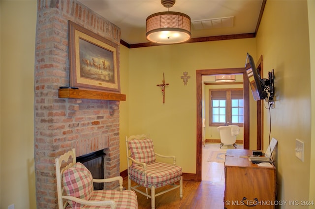 living area with crown molding, a fireplace, and wood-type flooring