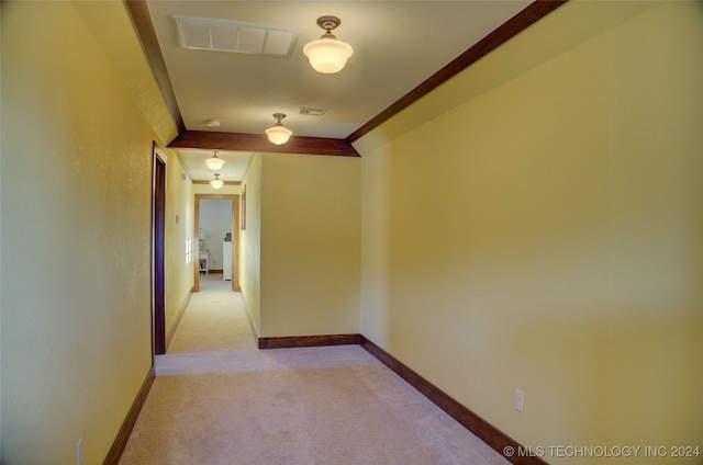 corridor with ornamental molding and light carpet